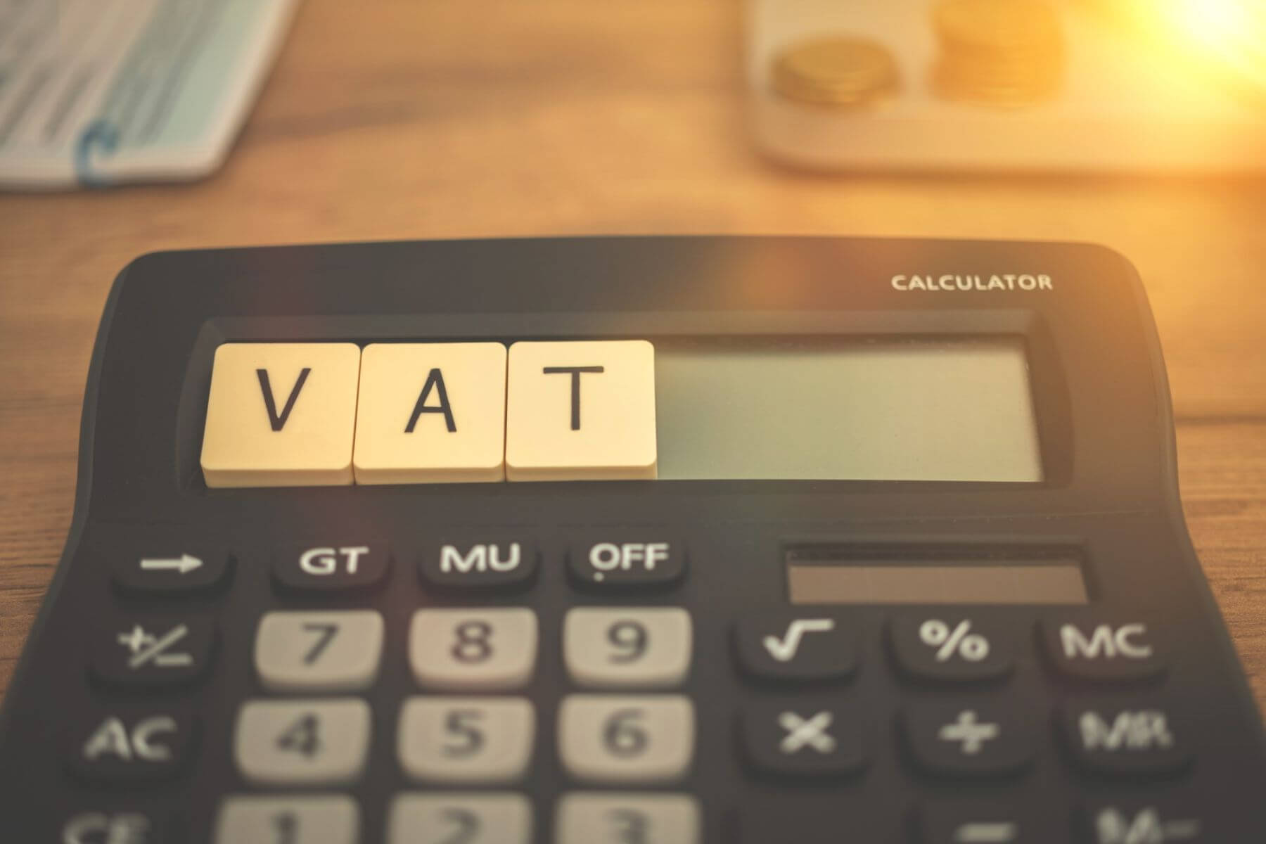 stawki vat hiszpania: kalkulator, na którym leżą scrabble z napisem VAT